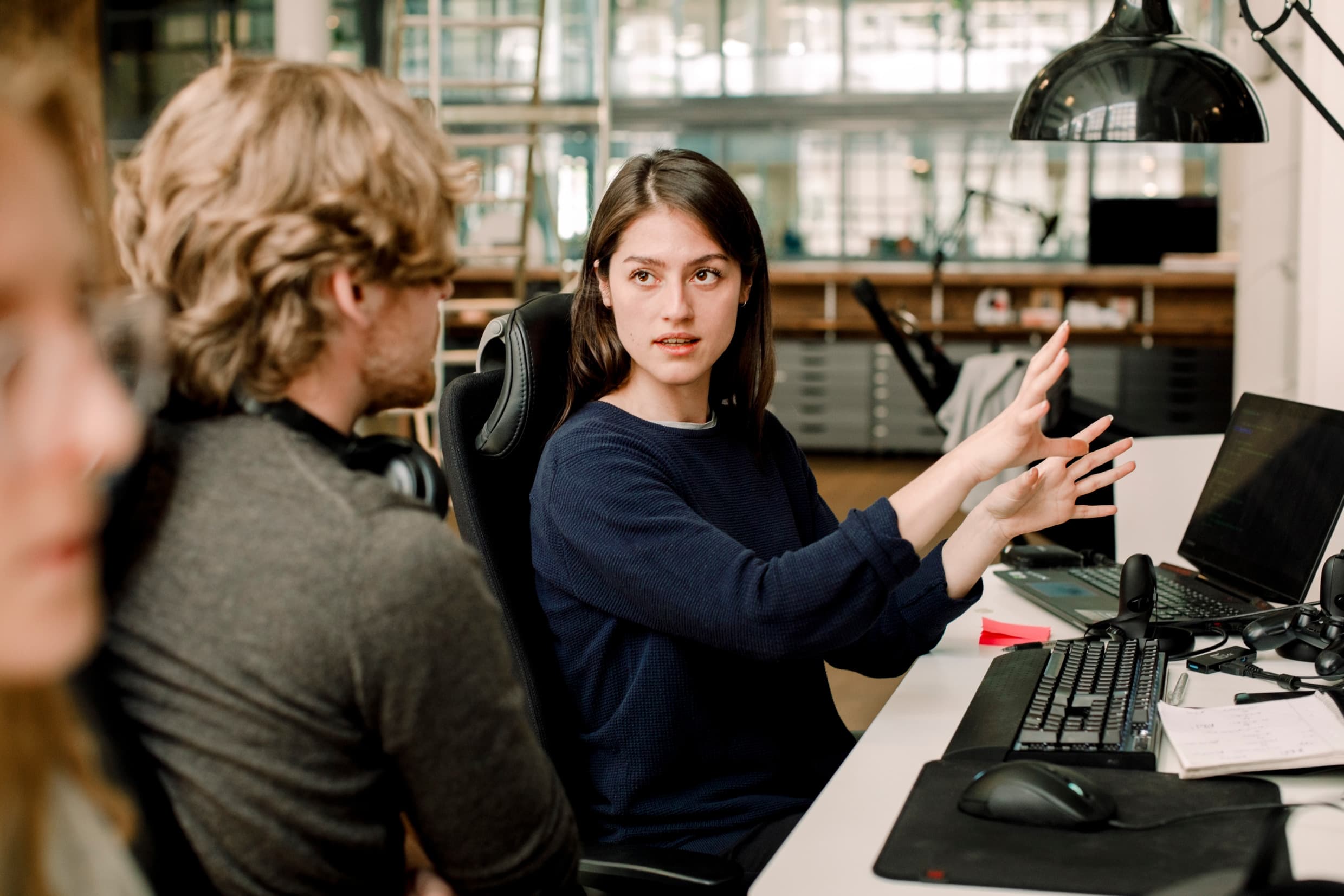 Two colleagues discussing work at a desk in a bright office