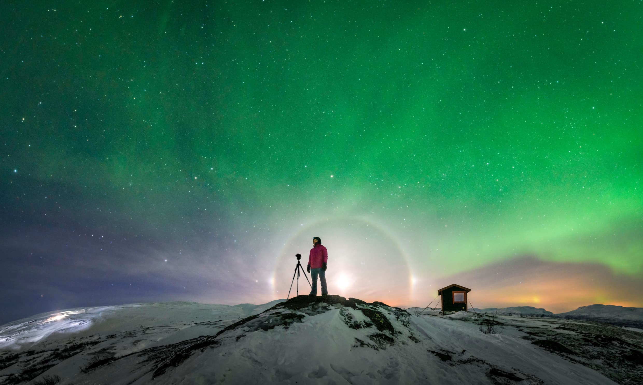 The northern lights over a snow-covered landscape in the Nordics